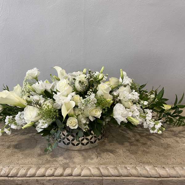 Low white floral arrangement in a decorative silver bowl