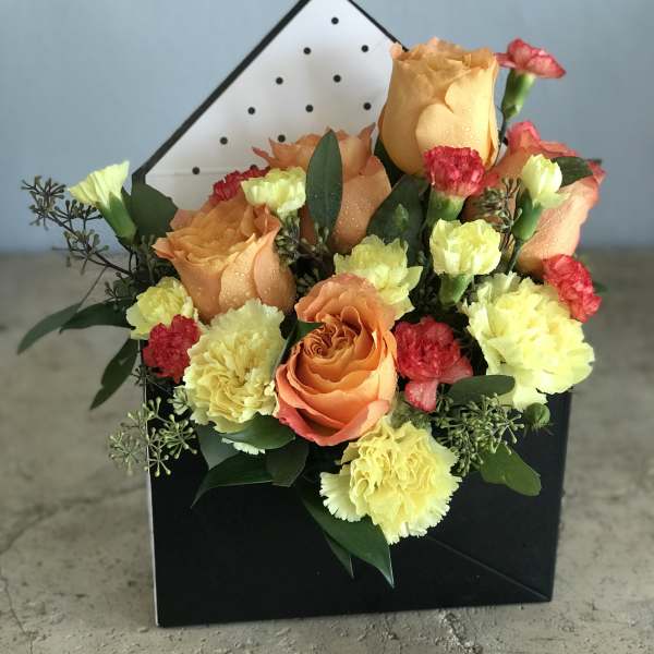 Orange roses and yellow carnations in a black gift box