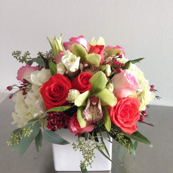 Mixed bouquet of red and pink roses with white blooms in a white vase
