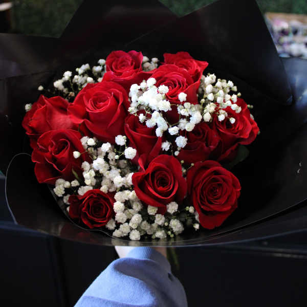 Bouquet of red roses with white baby's breath in black wrap