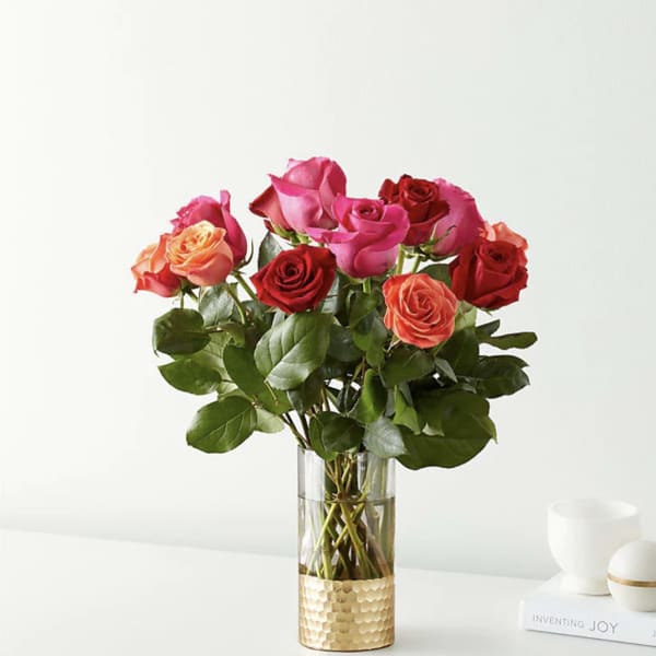 Bouquet of red, pink, and peach roses in a clear glass vase