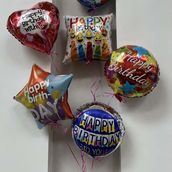 Cluster of colorful birthday balloons against a wall