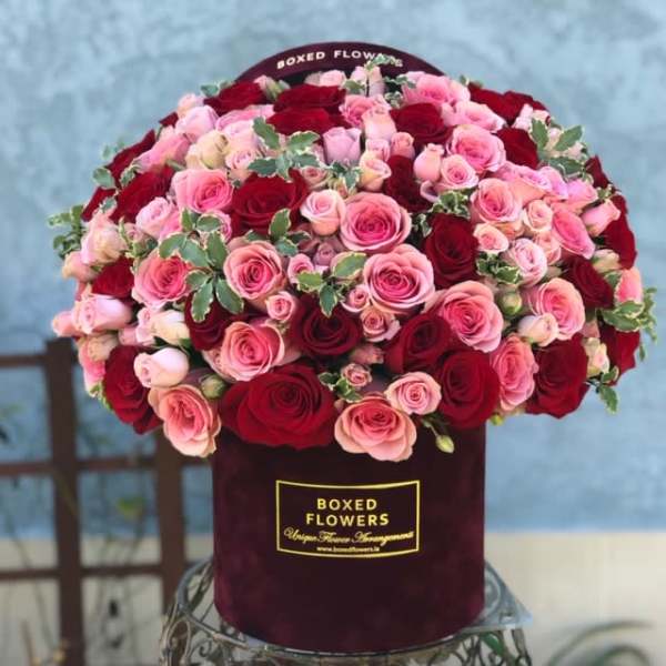 Boxed arrangement of pink and red roses in a burgundy hatbox