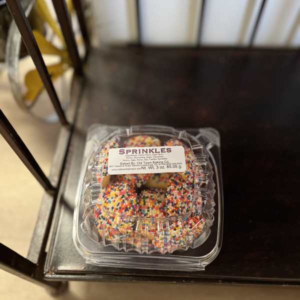Plastic clamshell container of sprinkle-covered cookies on a chair