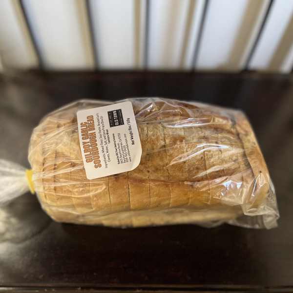 Wrapped loaf of sourdough bread on a dark table