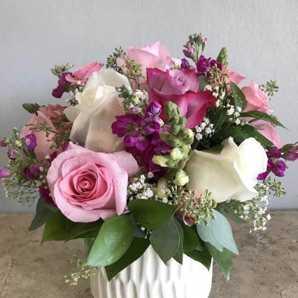 Pink and white roses arranged in a white vase.