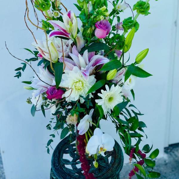 Tall floral arrangement with lilies, roses, and white daisies in a decorative vase