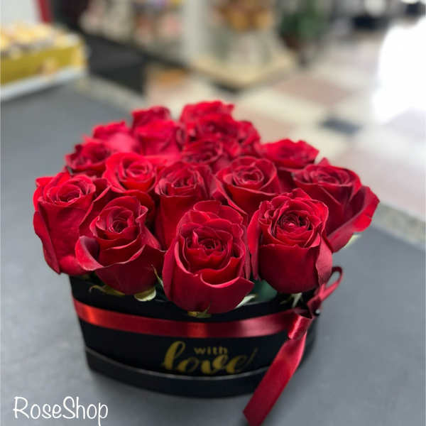 Red roses arranged in a black hat box with a red ribbon