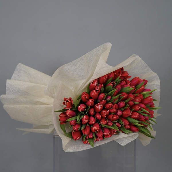 Bouquet of red tulips wrapped in white paper