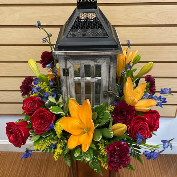 Lantern centerpiece surrounded by red roses and yellow lilies