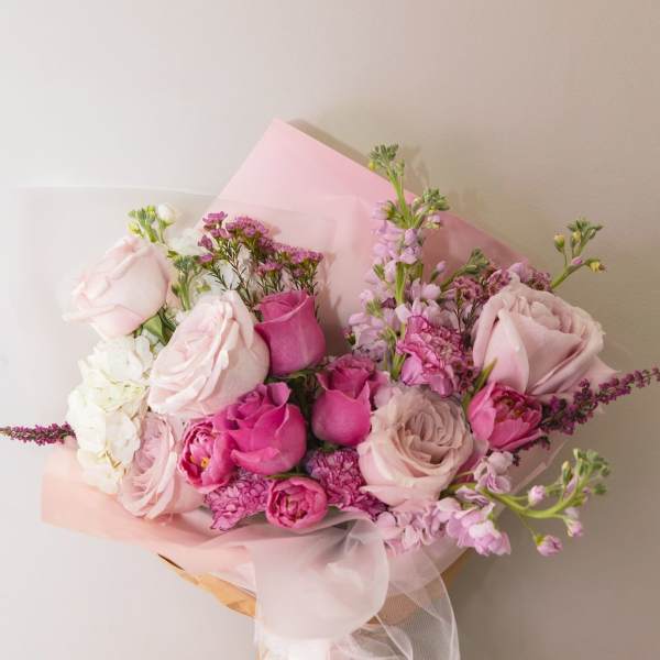 Pink and white mixed bouquet wrapped in translucent paper with a ribbon