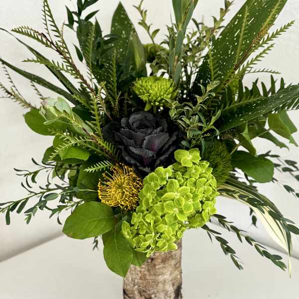 Green floral arrangement in a birch bark vase with bright lime blooms