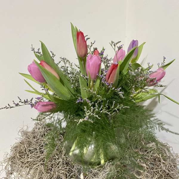 Pink and purple tulips in a glass vase with airy filler