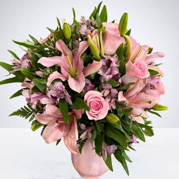 Pink lilies and roses arranged in a pink vase