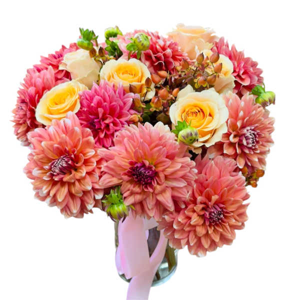 Pink and peach bouquet of dahlias and roses in a glass vase with a ribbon