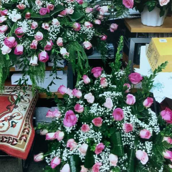 Large pink rose arrangements with baby's breath in white containers