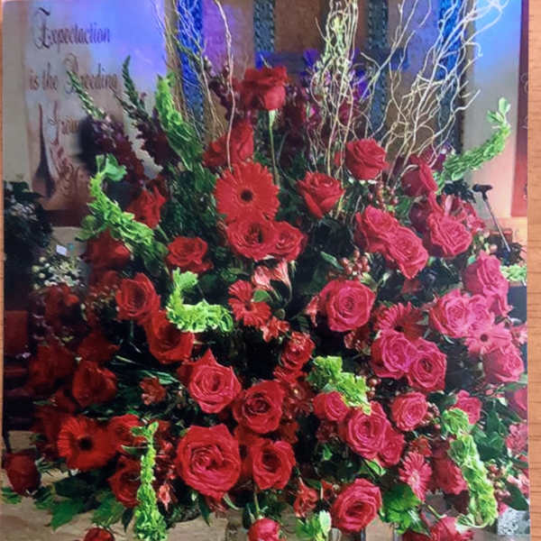 Large red and pink rose arrangement in a tall vase
