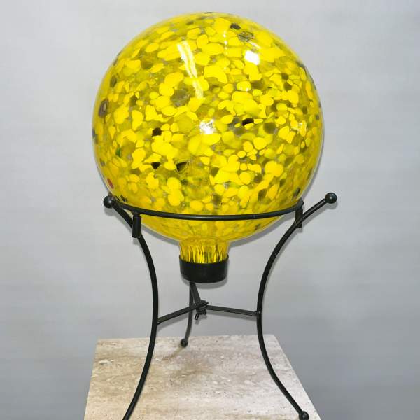 Yellow glass orb on a black metal stand