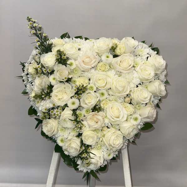 Heart-shaped arrangement of white roses and daisies on an easel