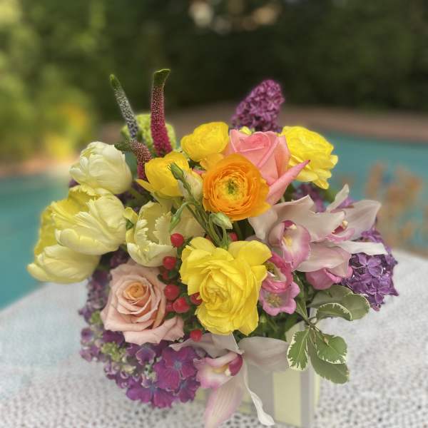 Colorful bouquet of roses, ranunculus, tulips, and orchids in a vase
