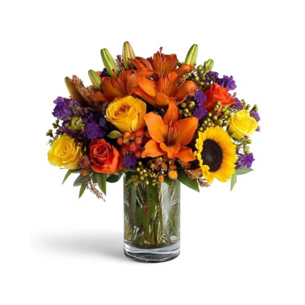 Bright mixed bouquet of orange, yellow, and purple flowers in a glass vase