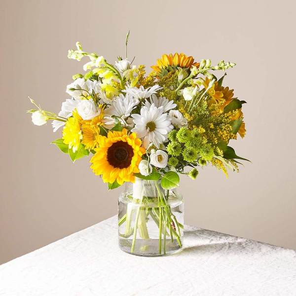 Bouquet of sunflowers and white daisies in a clear glass vase