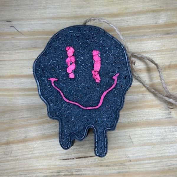 Black skull-shaped hanging ornament with a pink smiley face