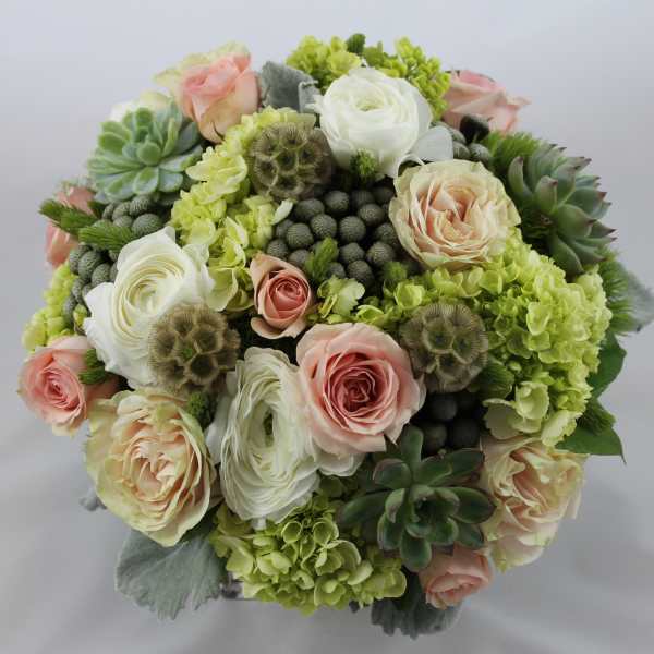 Round bouquet of pale roses, white blooms, and succulents