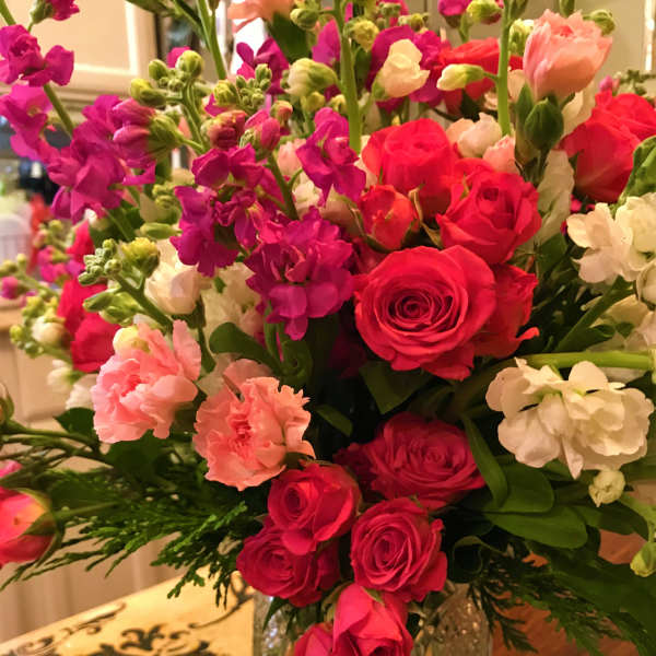Bouquet of pink roses, carnations, and purple blooms in a glass vase
