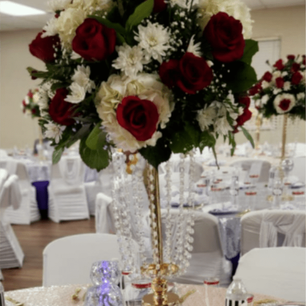 Tall centerpiece with red roses and white flowers in a gold stand