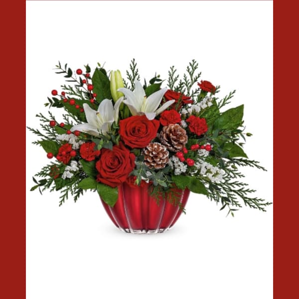 Red roses and white lilies in a red vase with pinecones and berries