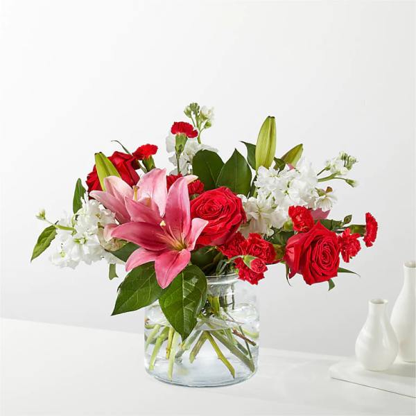Bouquet of red roses, pink lilies, and white flowers in a glass vase