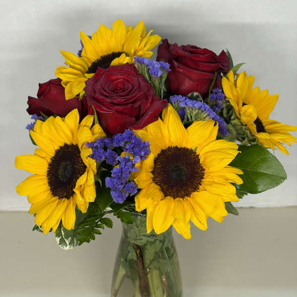 Bouquet of red roses and yellow sunflowers in a glass vase