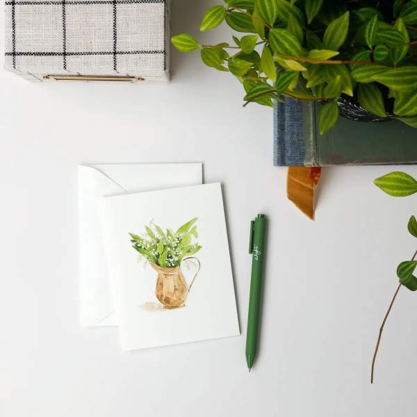 Greeting card with a watercolor potted plant illustration beside an envelope and pen