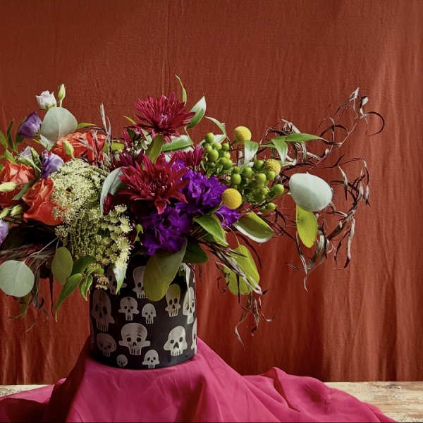 Colorful mixed bouquet in a black skull-patterned container