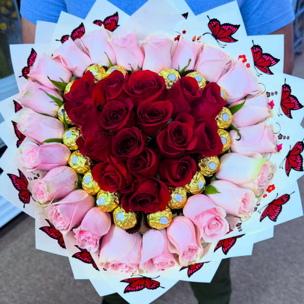 Heart-shaped bouquet of red and pink roses with gold-wrapped chocolates