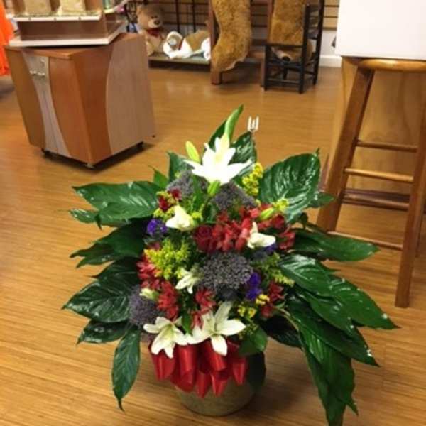 Mixed flower arrangement in a low container with white lilies and red blooms