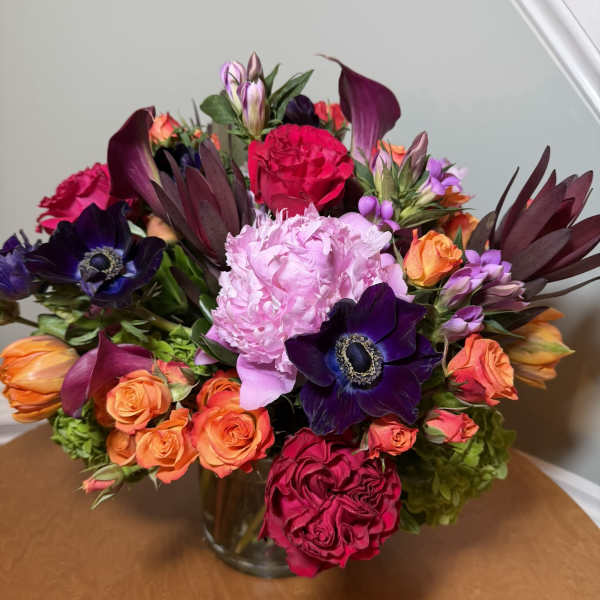 Mixed bouquet of pink, orange, and purple flowers in a glass vase