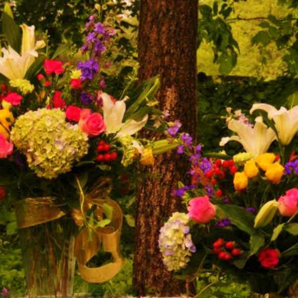 Two colorful floral arrangements with lilies, roses, and hydrangeas outdoors