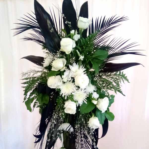 White floral standing spray with dark foliage on a stand