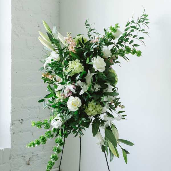Tall white floral arrangement on a black stand