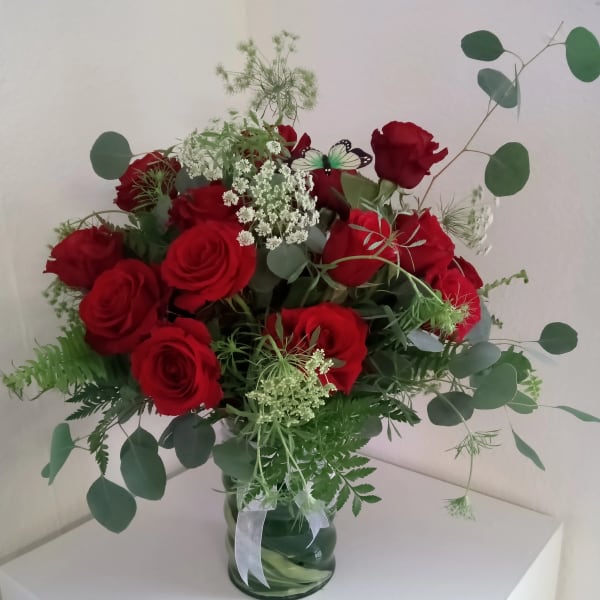 Red roses in a glass vase with airy white filler and eucalyptus