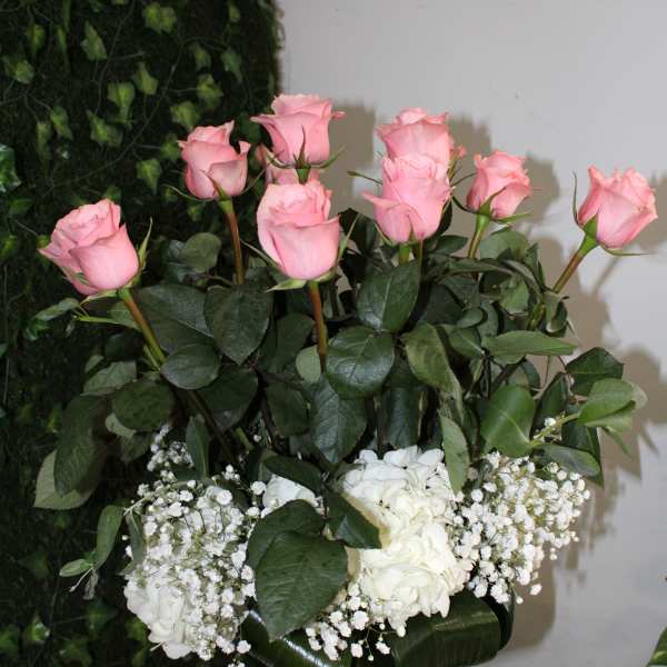 Pink roses and white flowers arranged in a clear glass vase