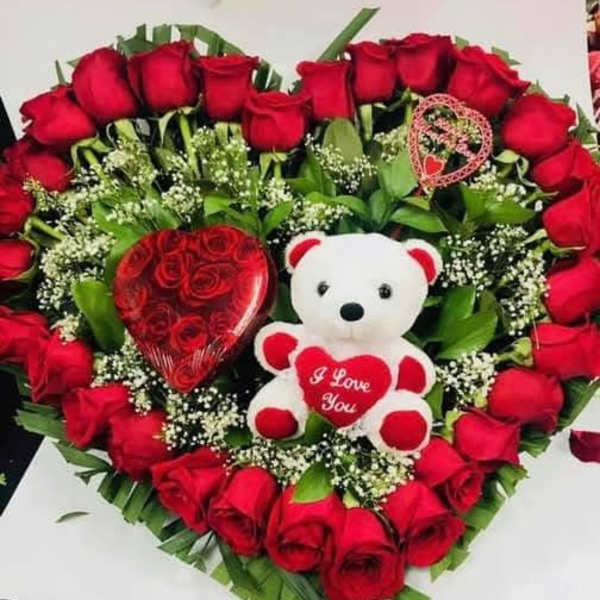 Heart-shaped rose arrangement with a teddy bear and heart decorations
