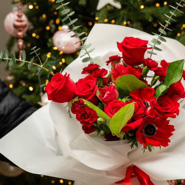Bouquet of red roses and red anemones wrapped in white paper