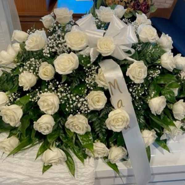 Large white rose casket spray with ribbon bows and baby's breath