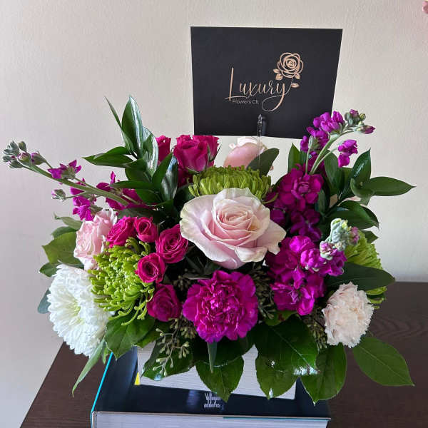 Pink and white roses with magenta blooms in a white box arrangement