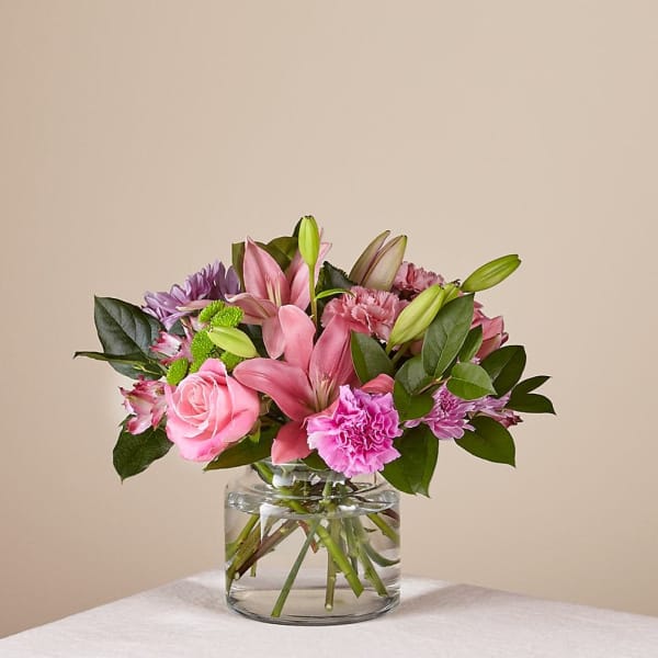 Pink lilies and roses in a clear glass vase