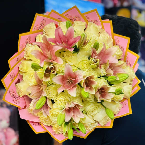 Bouquet of pale yellow roses and pink lilies wrapped in pink paper
