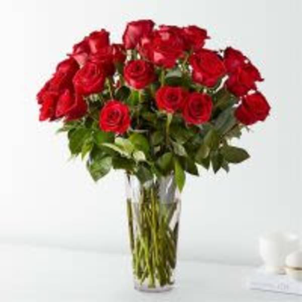 Tall arrangement of long-stem red roses in a clear glass vase